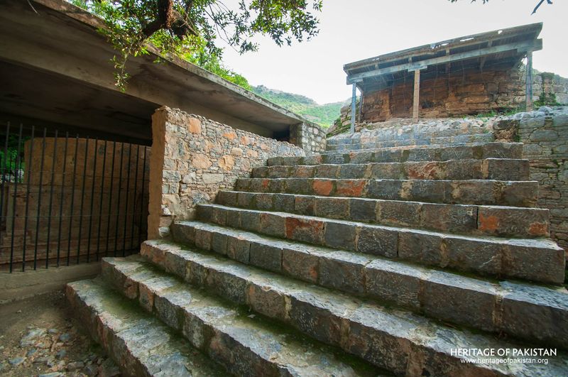 Protected stairway with weathered stone and mountain backdrop